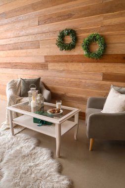 Gri koltuklar ve ahşap duvarın yanında Noel dekoru olan kahve masası.