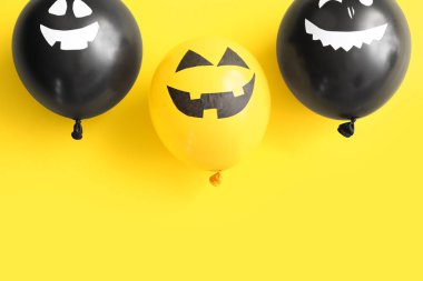 Sarı arka planda farklı komik Cadılar Bayramı balonları