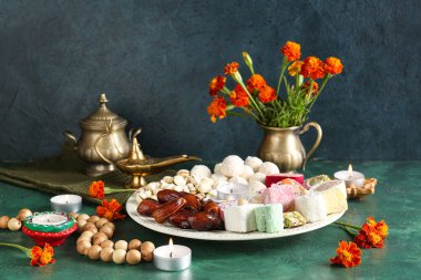 Mumlar, boncuklar, kadife çiçekleri ve grunge yeşil arka planda farklı tabaklar bulunan Diya lambaları. Divaly kutlaması