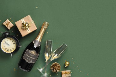 İçinde şampanya, çalar saat ve yeşil arka planda Noel hediyeleri olan kompozisyon