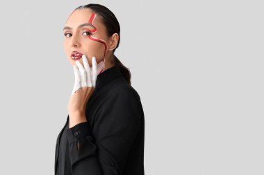 Işıklı arka planda yüzü boyalı genç bir kadın.