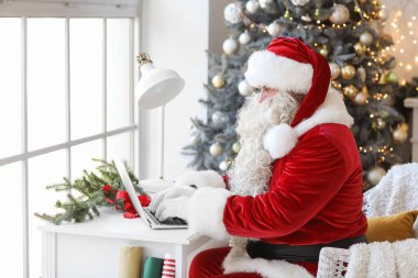 Noel Baba evde dizüstü bilgisayar kullanıyor.