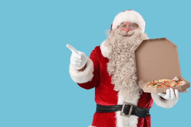 Bir kutu lezzetli pizzayla Noel Baba mavi arka plandaki bir şeyi işaret ediyor.
