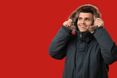 Kırmızı arka planda şık kabarık ceketli genç adam.