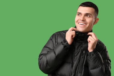 Yeşil arka planda siyah şık kabarık ceketli genç adam.
