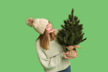 Yeşil arka planda Noel ağacı olan güzel genç bir kadın.