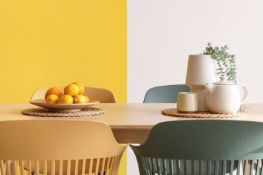 Yemek masasında renkli duvarın yanında bitki ve çaydanlık bulunan kenevirler.