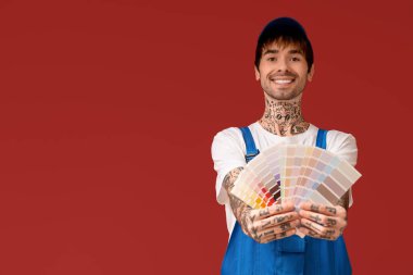 Renk arkaplanında palet örnekleri olan mutlu erkek ressam