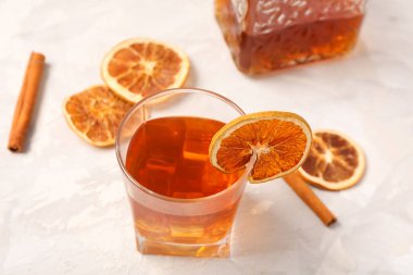 Bir bardak lezzetli eski moda kokteyl. Kurumuş portakal dilimleri ve tarçın çubukları beyaz grunge arka planda.