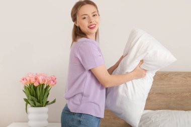 Yatak odasında yastığı koyan güzel bir genç kadın.