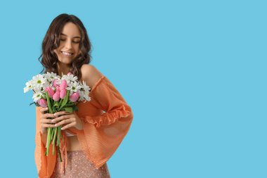 Mavi arka planda bahar çiçekleri olan güzel genç bir kadın.