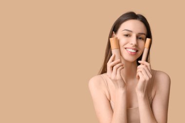 Portrait of beautiful young woman with foundation and concealer on brown background