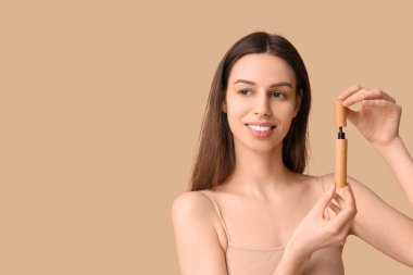 Beautiful young woman with mascara on brown background