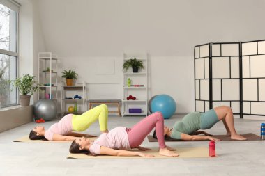 Güzel, genç, sportif, hamile kadınlar spor salonunda yoga yapıyor.