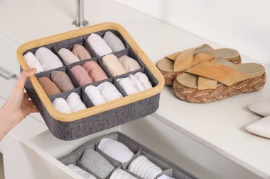 Dolaptaki organizatörlerde temiz giysileri olan güzel genç bir kadın, yakın plan.