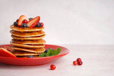 Beyaz arka planda lezzetli krep, çilek ve yaban mersini tabağı