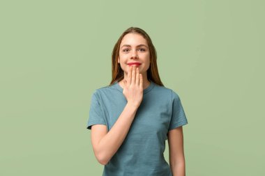 Young deaf mute woman using sign language on green background
