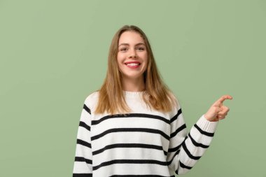 Young deaf mute woman using sign language on green background