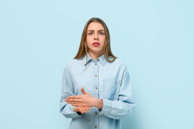 Young deaf mute woman using sign language on blue background