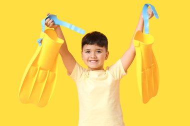 Sarı arka planda paletleri olan sevimli küçük bir çocuk.