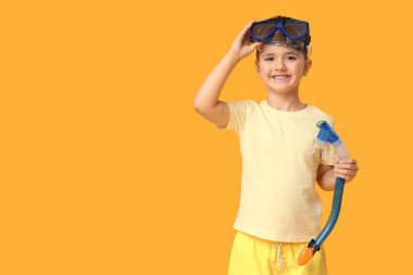 Sarı arka planda tüp takmış, yüzme maskeli şirin bir çocuk.