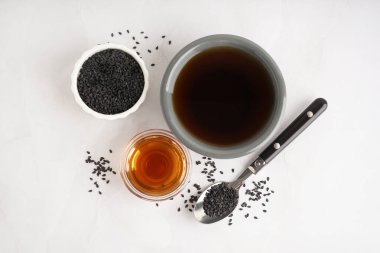 Beyaz arka planda kaşıkla yağ ve susam tohumları.