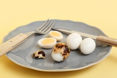 Sarı arka planda taze kaynamış bıldırcın yumurtası tabağı.