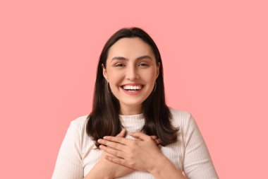 Pembe arka planda gülümseyen genç kadın