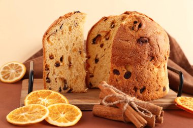 Lezzetli Panettone ile ahşap tepsi, kahverengi masada kurutulmuş portakal dilimleri ve tarçın çubukları
