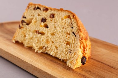 Gri arkaplanda Panettone parçası olan ahşap tepsi