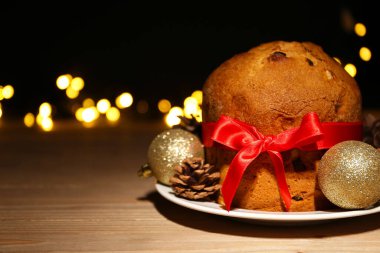 Lezzetli Panettone tabağı, Noel topları ve ahşap masa konisi.