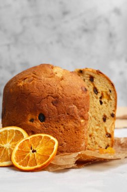 Gri arkaplanla parşömen üzerinde bir dilim turuncu panettone