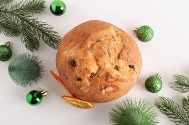 Noel toplarıyla Lezzetli Panettone, kurutulmuş portakal dilimleri ve beyaz arka planda köknar ağacı dalları
