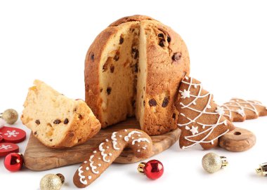 Kesik Panettone, kurabiyeler ve beyaz arka planda Noel dekoru olan ahşap tahta.