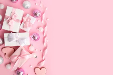 Toplu Noel hediyesi kutuları, kalp şeklinde kurabiyeler ve pembe arka planda kurdele.