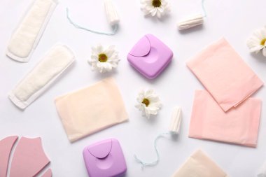 Beyaz arka planda tampon, depolama kutuları ve papatya çiçekleri olan adet pedleri