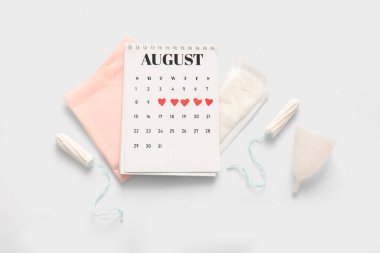 Beyaz arka planda pedleri, tamponları ve fincanı olan adet takvimi