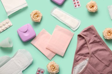 Yeşil arka planda pedli, fincanlı, haplı ve gül çiçekli iç çamaşırı.