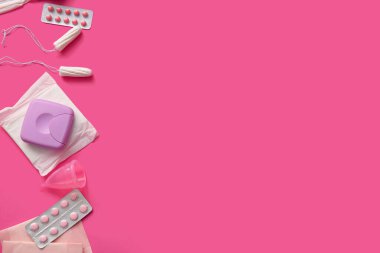 Tamponlu, fincanlı, depolama kutulu ve pembe arka planda haplı adet pedleri