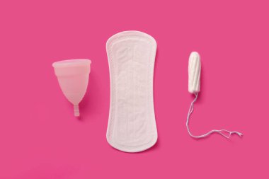 Pembe arka planda tampon ve fincanlı adet pedi.