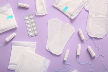 Adet pedleri, tamponlar ve mor arka planda haplar.