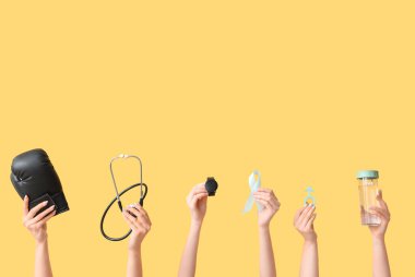 Boks eldivenli kadın eller, steteskop, kol saati, açık mavi kurdele ve sarı arka planda erkek işareti. Prostat kanseri kavramı