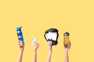 Su şişeli kadın eller, açık mavi kurdele ve sarı arka planda boks eldivenleri. Prostat kanseri kavramı