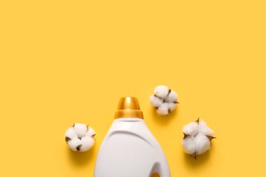 Bottle of laundry detergent with cotton flowers on yellow background clipart