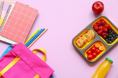 Lezzetli yemekler, okul kırtasiyesi ve leylak arkaplanlı sırt çantası.