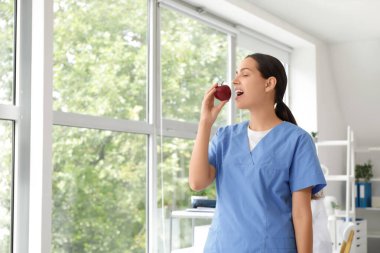 Klinikte elma yiyen genç bayan doktor.