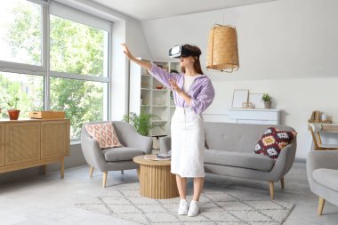 Evde VR gözlük takan genç bir kadın.