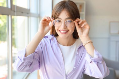 Gözlüklü genç kadın pencerenin yanında, yakın plan.