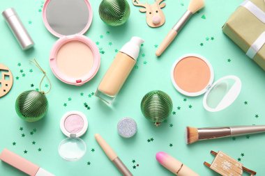 Farklı makyaj ürünleri ve yeşil arka planda Noel dekoru