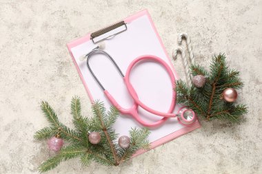 Beyaz grunge arka planında pano ve Noel dekoru olan stetoskop